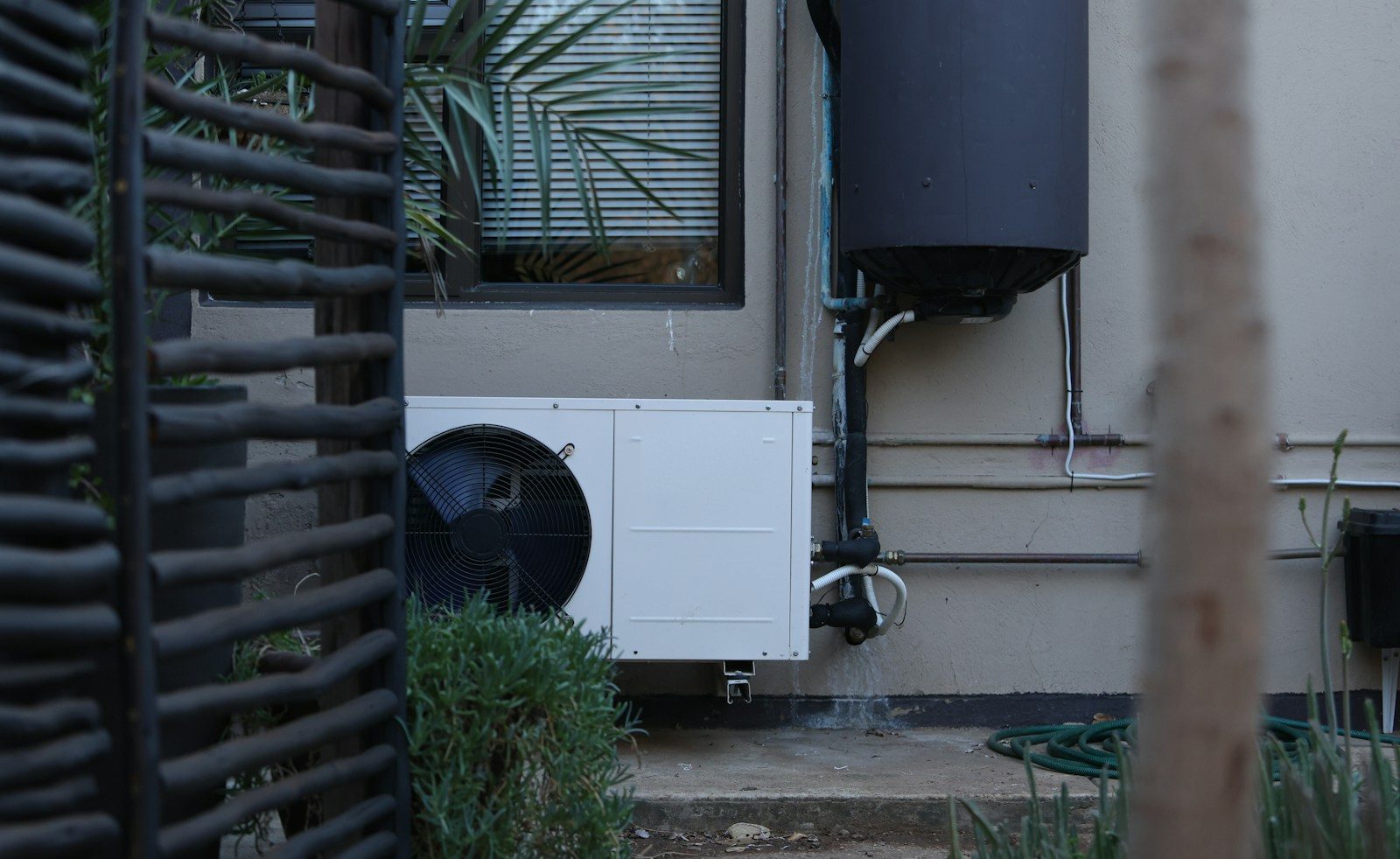 Heat pump AC unit beside a Tucson home with desert plants